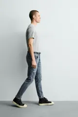 Jeans skinny fit de corte ajustado y tiro medio en color negro con efecto lavado y detalles desgastados. Confeccionados en tejido elástico con mezcla de algodón, presentan diseño clásico de cinco bolsillos y cierre frontal con cremallera y botón.