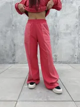 Pantalon de corte recto y holgado en color rojo, con cintura elastizada y bolsillos laterales funcionales. Presenta un diseño con costuras verticales que crean un efecto de relieve en el frente.