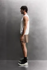 Pantalón corto deportivo color marrón oliva, confeccionado en tejido técnico ligero y elástico, con forro interior. Presenta cintura elástica ajustable con cordón, bolsillos frontales, bolsillo de seguridad trasero con cierre y aberturas laterales en el bajo.