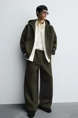 Pantalón de corte wide fit confeccionado en tejido técnico con efecto neopreno. Presenta cintura elástica ajustable con cordón, perneras anchas con costura frontal, bolsillos laterales y bolsillos traseros de plastrón.