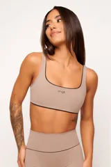 Conjunto deportivo de top y calzas color tostado, confeccionado en poliamida de alta performance con detalles de vivo contrastante. El top cuenta con breteles anchos y diseño slim, mientras que la calza presenta un diseño minimalista de tiro alto.