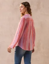 Blusa de gasa estampada con flores en tonos rosa, amarillo y azul. Tiene cuello a la base, escote en V y botones. La delantera tiene detalle plisado y las mangas son 3/4 regulables con presilla y botón.