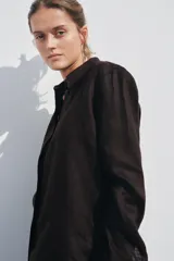 Camisa color coral confeccionada en lino 100%, de corte recto, con cuello solapa, manga larga con puños abotonados y cierre frontal con botones.