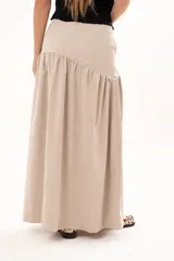 Pollera larga de corte evasé en color arena, con detalle de costura horizontal y frunces en la parte inferior que le otorgan volumen y movimiento.