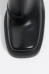 Botín de cuero negro con puntera cuadrada, cierre lateral con cremallera y tacón geométrico.