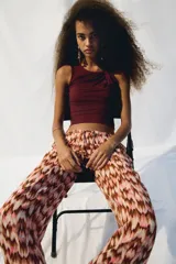 Top sin mangas color vino tinto, de tejido elástico y ajuste entallado, con un nudo drapeado en el hombro que crea un escote asimétrico.