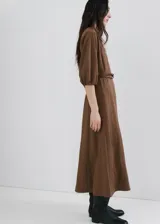 Vestido midi marrón de corte recto, con cuello redondo, mangas tres cuartos y detalle de cinturón fino en la cintura.