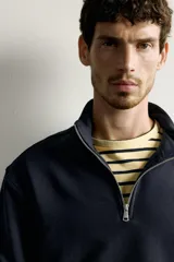 Sudadera negra de corte regular fit, con cuello subido, cierre frontal de cremallera corta y acabados en rib elástico en puños y cintura.