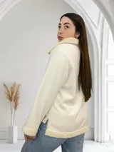 Campera color crudo de pana con cuello, puños y ruedo de corderito. Tiene cierre frontal y corte recto.