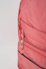 Mochila color rosado con múltiples compartimentos con cierre, asa superior acolchada y logo de la marca en la parte frontal inferior.