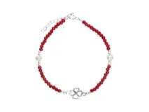 Pulsera de plata con cuentas facetadas de cristal rojo y dos perlas blancas. Incluye un dije central de trébol de cuatro hojas en plata.