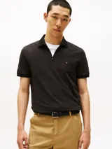Chomba negra de manga corta con cuello tipo polo y cierre de cremallera corto. Logo de Tommy Hilfiger bordado en el pecho. Confeccionada en algodón orgánico, poliéster reciclado y elastano.