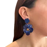 Aros colgantes con forma de flor hechos de resina color azul. Se ajustan con perforación y no contienen níquel.