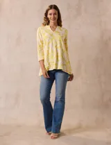 Blusa amarilla estampada con motivos florales en blanco, escote en V y mangas tres cuartos.