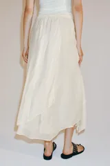 Falda midi fluida de tiro medio, color blanco, con cintura elástica ajustable mediante cordones y bajo asimétrico.