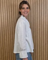 Blusa blanca de algodón con escote en V y cuello mao. Presenta mangas largas abullonadas con puños acampanados y fruncidos.