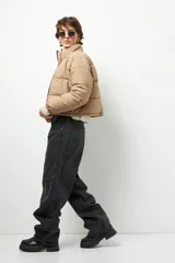 Campera puffer corta color beige de nylon, con cuello alto, cierre frontal y bolsillos laterales con cierre.