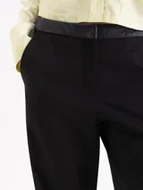 Pantalón de corte recto confeccionado en tela sastrera, con cintura de cuero vacuno, raya marcada en el centro de las piernas y bolsillos laterales.