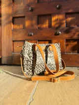 Cartera tipo tote bag con estampado animal print, doble asa de mano color cuero y correa larga desmontable y regulable.