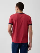 Remera de manga corta color rojo con detalles en azul marino en el cuello y los puños, cuenta con un bolsillo aplicado en el pecho.