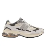 Championes urbanos New Balance modelo 2010, con diseño de paneles en tonos gris, beige y crema. Presentan una combinación de malla técnica y superposiciones de gamuza, con el logo N característico en el lateral y una entresuela robusta con detalles en color bronce.
