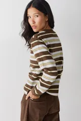 Bucito de manga larga con diseño de rayas horizontales en tonos marrón, blanco y amarillo. Presenta cuello redondo tejido y puños acanalados, con el logo de la marca bordado en el centro del pecho.