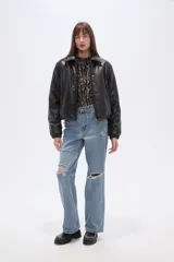 Campera estilo bomber de eco-cuero negra, con cuello camisero, cierre frontal y puños y cintura ajustados con elástico.