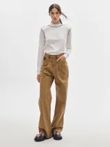 Pantalón jean de tiro alto y corte pinzado, con perneras de caída suelta y levemente anchas en el bajo. Posee pasador con hebilla en la parte trasera.