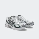 Championes Asics modelo Gel 1130, con diseño retro inspirado en el running de los años 2000. Presenta una base de malla blanca con superposiciones en cuero sintético plateado y detalles en verde oscuro. Incorpora tecnología GEL en el talón para mayor amortiguación y suela de goma blanca.