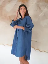 Vestido camisero de denim suave en tono celeste claro, con cuello mao, cierre frontal de botones y mangas tres cuartos con puños elásticos.