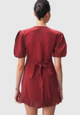 Vestido corto de rayón color negro, con diseño cruzado (wrap dress), escote en V, mangas cortas abullonadas y detalle de volados en el ruedo y lateral.