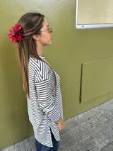 Remerón de manga larga con diseño de rayas horizontales finas en color negro sobre fondo blanco. Presenta un corte oversize, cuello redondo y un largo asimétrico con la parte trasera ligeramente más larga que la delantera.