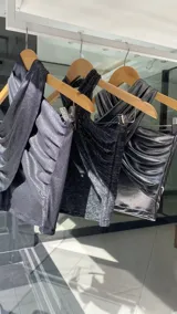 Top negro con diseño cruzado en el frente, estilo halter y con detalles de tachas doradas.