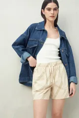 Short de algodón con cintura elastizada y cordón regulable, de calce relajado. Presenta bolsillos delanteros y un diseño de rayas diagonales en color verde sobre fondo beige.