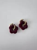 Aros de acero quirúrgico dorados con dijes colgantes en forma de flor de resina color bordó.