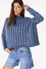 Sweater crop de punto con diseño de trenzas en relieve, color azul, cuello redondo y mangas largas. Cuenta con una pequeña etiqueta rectangular con el logo de la marca en el lateral inferior.