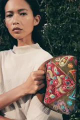 Bolso tipo caja con asa de mano rígida de madera, confeccionado con paneles de tela bordados con motivos florales, paisley y detalles en hilo metalizado.