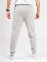 Pantalón de jogging gris melange, corte babucha, con cintura elástica ajustable con cordón y puños en los tobillos. Confeccionado en tejido de punto sin felpa.