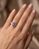 Anillo de plata con piedra central tallada en corte ovalado de color fucsia, rodeada por un doble pavé de circones brillantes.
