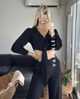 Conjunto color beige compuesto por un top corto con escote en V, botones frontales y mangas largas abullonadas con puños elásticos, y un pantalón de tiro alto con lazo en la cintura.