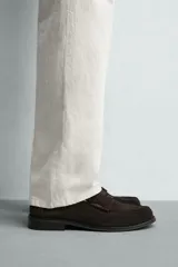 Mocasín de vestir para hombre, fabricado en piel con acabado en serraje de color azul marino. Presenta un diseño clásico con detalle de antifaz en el empeine, horma redonda, costuras visibles en el contorno y una suela sutil con ligero tacón.