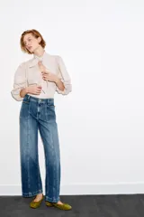Jeans de tiro alto con corte culotte y pernera ancha. Presenta bolsillos de plastrón en el frente con detalle de pespuntes decorativos en forma de onda y costuras verticales a lo largo de la pierna. Cierre frontal con cremallera y botón metálico.