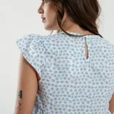 Blusa beige con estampado de líneas horizontales y verticales blancas, corte holgado y mangas cortas con volados.