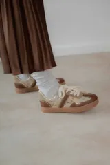 Championes urbanos de diseño acolchado, combinando tonos marrones, beige y detalles metalizados con textura. Cuentan con cordones al tono y suela de goma color caramelo.