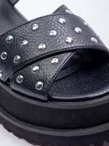 Sandalias negras de plataforma con doble tira cruzada sobre el empeine, tachas plateadas y ajuste con hebilla en el tobillo.