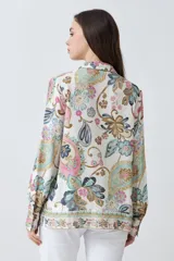 Camisa de manga larga con estampado de arabescos en tonos rosa, celeste, marrón y verde agua sobre fondo blanco. Tiene cuello clásico y cierre con botones.
