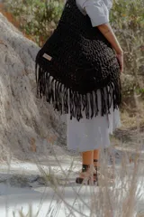 Bolso de mano grande tejido a crochet con técnica de trapillo reciclado, color beige visón. Presenta un diseño de punto grueso y flecos largos en el borde inferior.