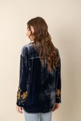Blusa de terciopelo azul con bordados multicolores, cuello mao y botones forrados.