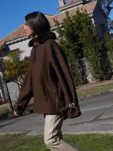 Buzo color crudo con cuello de piel sintética color crema, abertura parcial con cierre de cuero marrón y hebilla dorada, puños con ajuste de cuero marrón y bolsillos laterales.