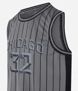 Musculosa deportiva de básquet gris con rayas verticales negras, cuello redondo y sisas con ribete negro. Estampado frontal con la palabra "Chicago" y el número "32".